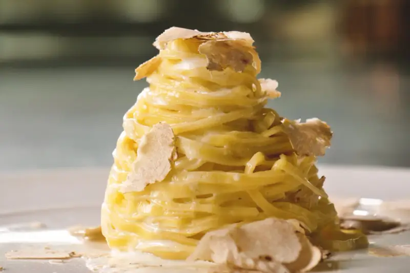 Un nido di pasta al tartufo, condita con una cremosa salsa e guarnita con scaglie sottili di tartufo bianco.
